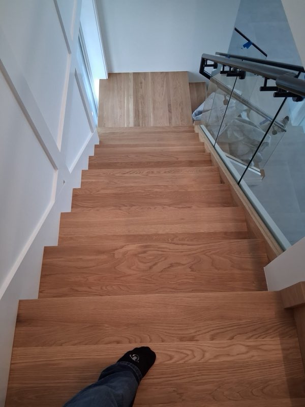 Stair refinish alongside a glass railing